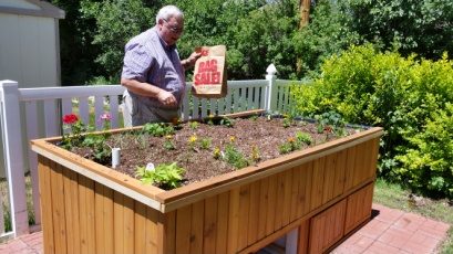 A man standing behind the finished cedar raised garden bed