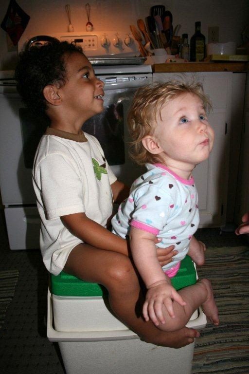 A small boy and a toddler girl sharing a step stool in a kitchen