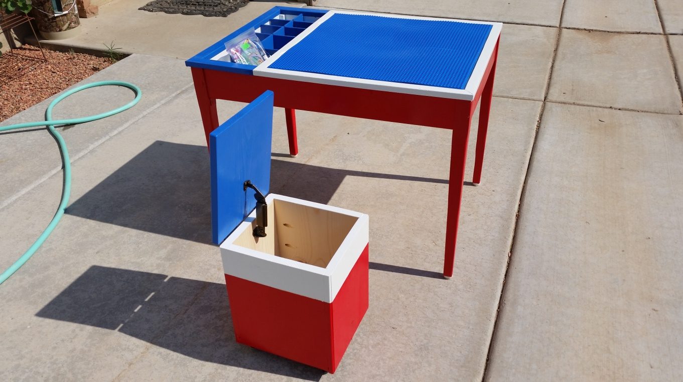A red-legged Lego table with a blue play surface, and a matching lidded storage bench with the lid propped open